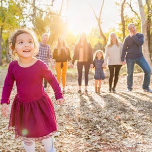 A little girl joyfully running in the park alongside her family - The Lawler Group